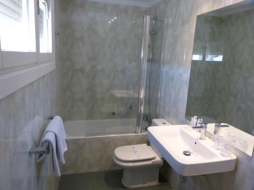 a bathroom with a sink and a toilet and a shower at Hotel Avenida in Zaragoza