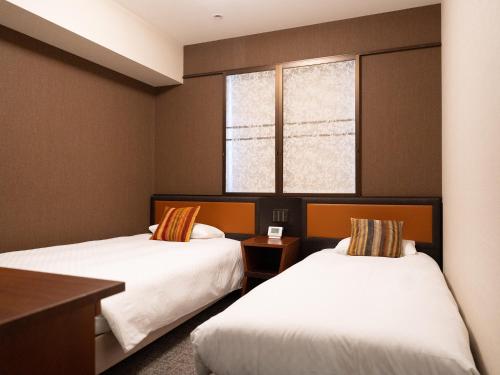 a hotel room with two beds and a window at Hearton Hotel Kita Umeda in Osaka