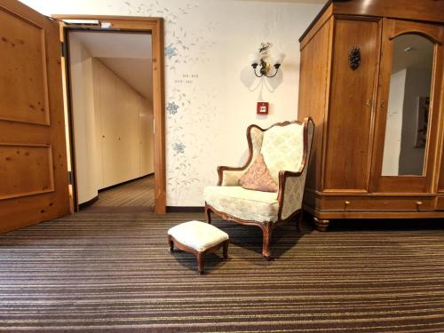 a living room with a chair and a ottoman at Mosers Blume Relax & Genuss Hotel in Haslach im Kinzigtal