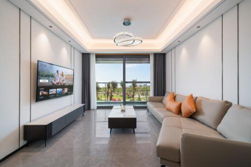 a living room with a couch and a tv at Puhai Sea View Apt by Hailan Tour at Sanya Yazhou Bay#only 100 meters to Beach and Sea Swimming Area in Sanya