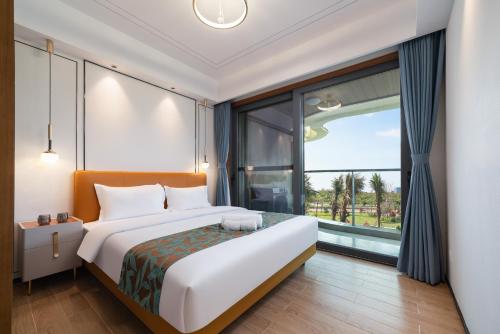 a bedroom with a large bed and a large window at Puhai Sea View Apt by Hailan Tour at Sanya Yazhou Bay#only 100 meters to Beach and Sea Swimming Area in Sanya