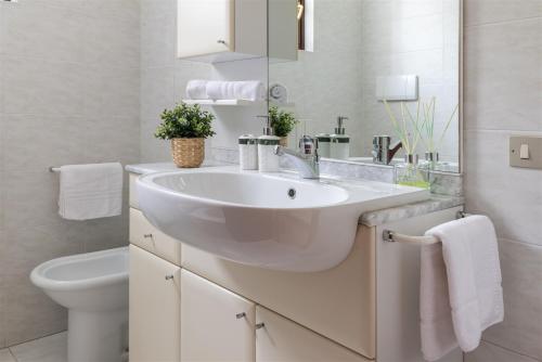 a white bathroom with a sink and a toilet at IseoLakeRental - Bosco di Lago in Solto Collina