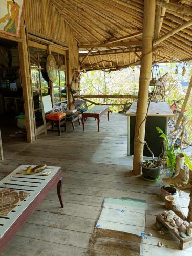 a porch of a house with benches and tables at Sunrise Villa in Maluk