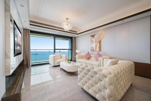 a living room with a white couch and a large window at Puhai Sea View Apt by Hailan Tour at Sanya Yazhou Bay#only 100 meters to Beach and Sea Swimming Area in Sanya