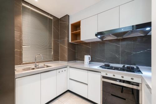 a kitchen with white cabinets and a sink and a stove at Puhai Sea View Apt by Hailan Tour at Sanya Yazhou Bay#only 100 meters to Beach and Sea Swimming Area in Sanya