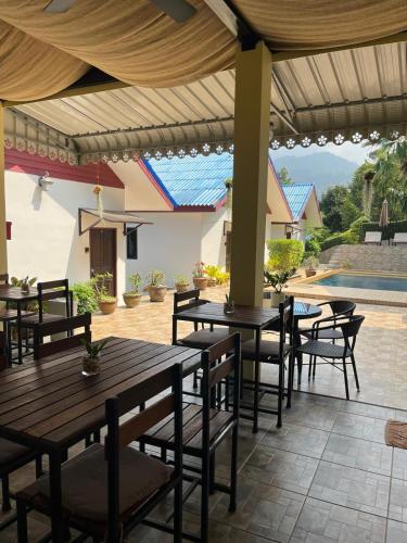 a patio with tables and chairs and a pool at Sawasdee Home Stay Resort & Pool in Khao Lak