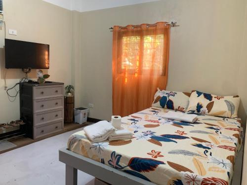 a bedroom with a bed and a dresser and a television at G-Bay Farm Village in Malolos
