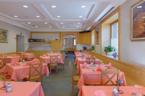 アウロンツォ・ディ・カドーレにあるHotel La Nuova Montaninaのピンクのテーブルと椅子が備わるダイニングルーム