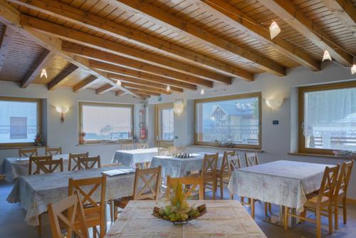 a dining room with tables and chairs and windows at Hotel La Nuova Montanina in Auronzo di Cadore