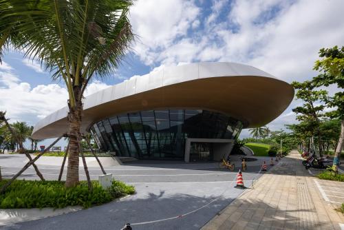 a building with a palm tree in front of it at Puhai Sea View Apt by Hailan Tour at Sanya Yazhou Bay#only 100 meters to Beach and Sea Swimming Area in Sanya
