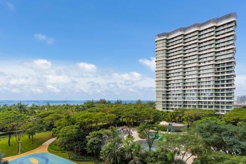 a tall building with a park and a resort at Puhai Sea View Apt by Hailan Tour at Sanya Yazhou Bay#only 100 meters to Beach and Sea Swimming Area in Sanya