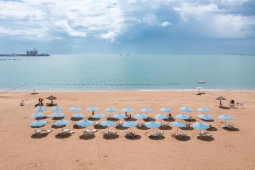 a group of chairs and umbrellas on a beach at Puhai Sea View Apt by Hailan Tour at Sanya Yazhou Bay#only 100 meters to Beach and Sea Swimming Area in Sanya