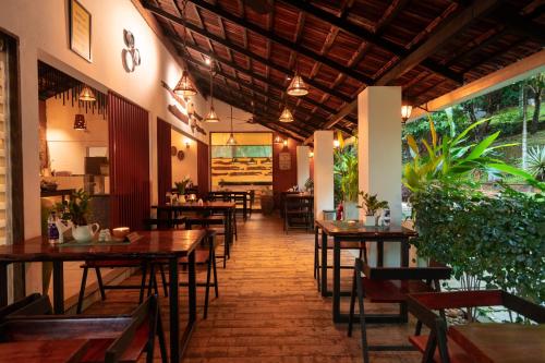 a restaurant with wooden tables and chairs and plants at Le Candles Resort in Kozhikode
