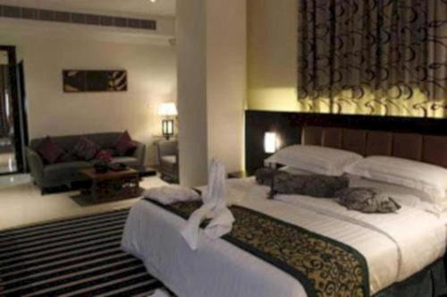 a bedroom with a large bed and a living room at Dancenter Luxury Millennia Near King Abdulaziz Historical Center in Riyadh