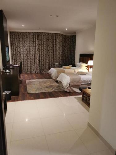 a large bedroom with two beds and a couch at Dancenter Luxury Millennia Near King Abdulaziz Historical Center in Riyadh