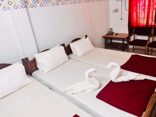 two white beds with swans on them in a room at shree katyayani residency in Gokarna