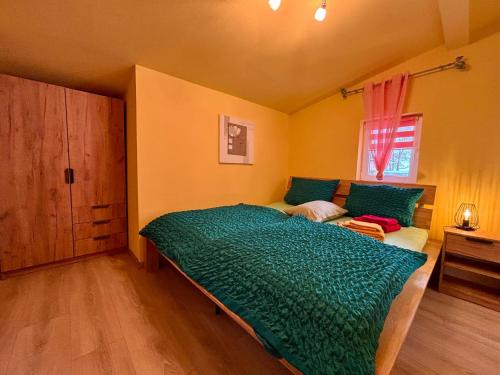 a bedroom with a bed with a green comforter and a window at Ferienhaus An der Riede in Bedekaspel