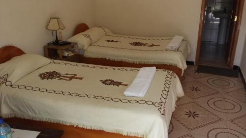 a room with three beds with white comforters at Lalibela Hotel in Lalībela