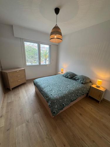 - une chambre avec un lit avec une couette bleue et 2 lampes dans l'établissement Les palmiers, à Cavalaire-sur-Mer