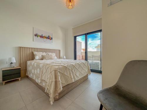 een slaapkamer met een bed, een stoel en een raam bij Barnuevo 3 in Santiago de la Ribera