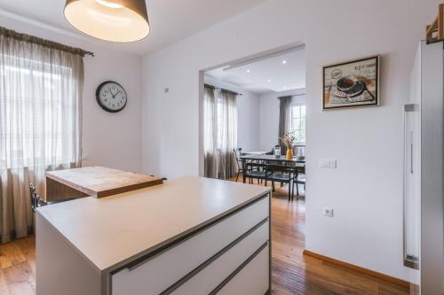 a kitchen with white walls and a clock on the wall at Apartment Vila Pavlovski in Bled