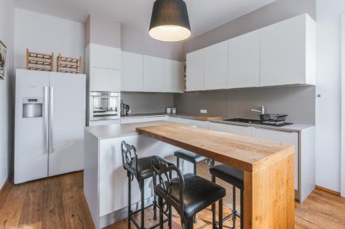 a kitchen with white cabinets and a wooden table and chairs at Apartment Vila Pavlovski in Bled
