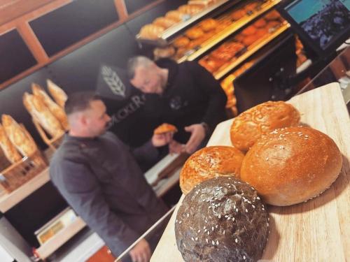 two men standing in a bakery with bread on a counter at Jägerhof Putzkau in Putzkau