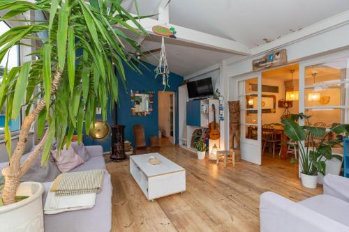 a living room with a couch and a palm tree at Board 'n Breakfast in Labenne