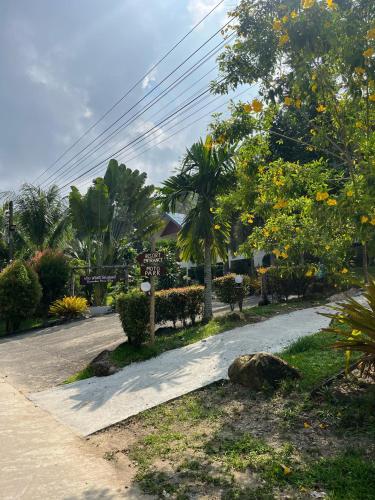 a street with trees and a sign on the side of a road at Sawasdee Home Stay Resort & Pool in Khao Lak