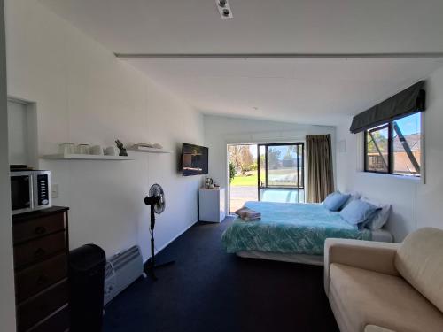 a bedroom with a bed and a couch at Shambala in Te Kauwhata