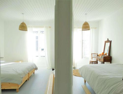 a white bedroom with two beds and a mirror at Palme - Saint Gilles Croix de Vie in Saint-Gilles-Croix-de-Vie
