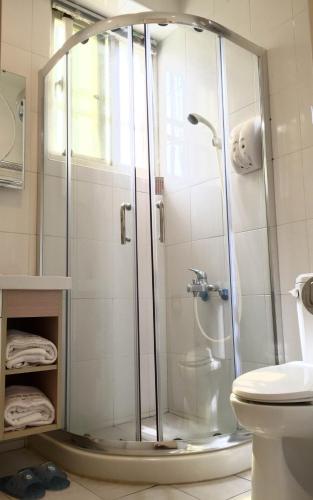 une douche avec une porte en verre dans une salle de bain dans l'établissement Backpacker B&B, à Jinning