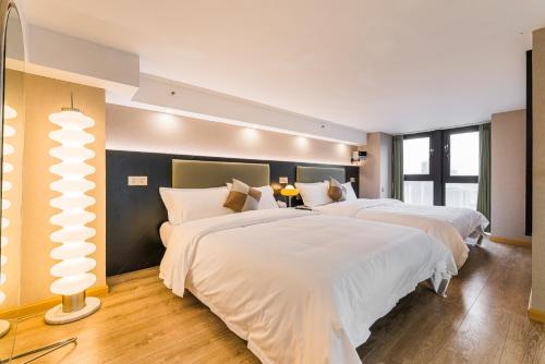 two beds in a hotel room with white sheets at 云享城居 SKY高空Loft公寓酒店 春熙路九眼桥店 in Chengdu