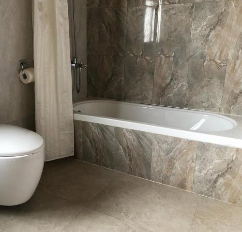 a bathroom with a bath tub and a toilet at Risum Resort in Ha