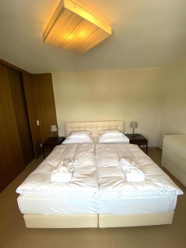 a large white bed with two white towels on it at Ferienwohnung mit Seesicht und Hotelservices in Maria Wörth
