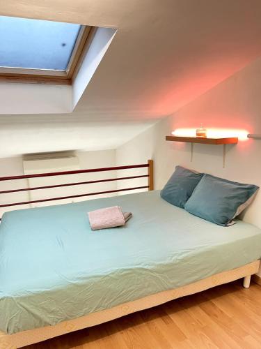 une chambre avec un grand lit avec des oreillers bleus dans l'établissement Appartement Coeur de Ville avec Terrasse et Parking, à Bergerac