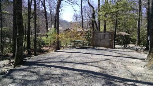 a picnic table and a bench in the woods at Linville Falls Campground, RV Park, and Cabins in Linville Falls