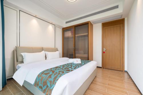 a bedroom with a large white bed and a door at Puhai Sea View Apt by Hailan Tour at Sanya Yazhou Bay#only 100 meters to Beach and Sea Swimming Area in Sanya