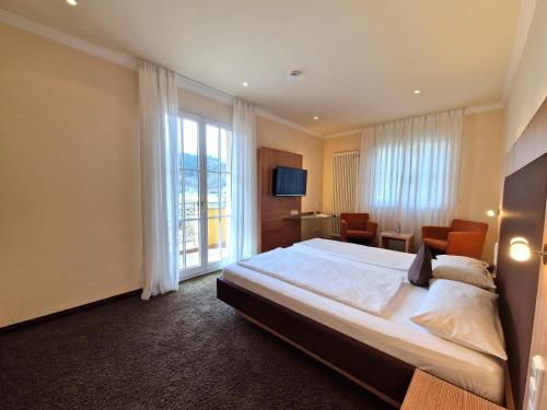 a bedroom with a large bed and a large window at Mosers Blume Relax & Genuss Hotel in Haslach im Kinzigtal