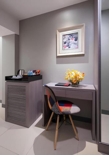 a desk with a chair and a vase of flowers at Solace Hotel in Manila