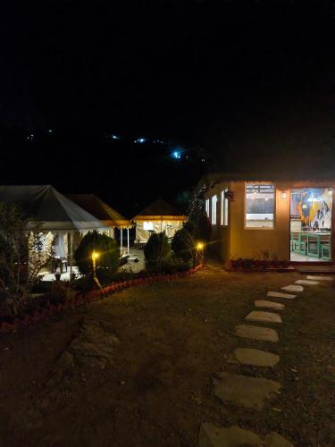 a building at night with lights in the yard at Shakoon Camps & Farmstay Nainital in Nainital