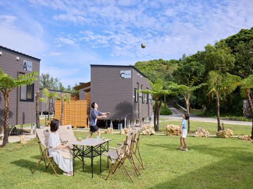 a group of people playing with a ball at a table in a yard at Yambaru Experience Hotel Nunganiku in Higashi