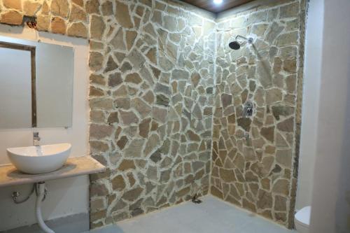 a bathroom with a shower with a stone wall at Neels Camp Resorts in Panna