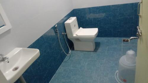a blue tiled bathroom with a sink and a toilet at Nilton Bay Residency in Kottakupam