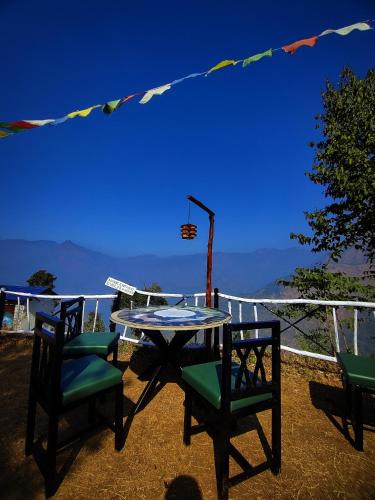 a table and chairs on a balcony with a view at Shakoon Camps & Farmstay Nainital in Nainital