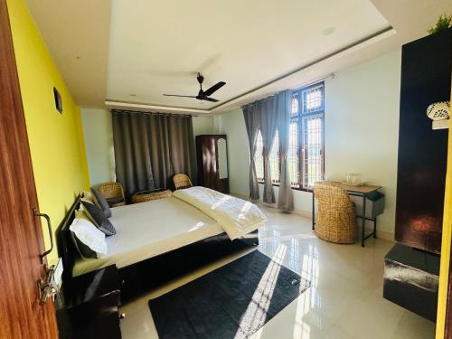 a bedroom with a bed and a table and windows at Ranghar Homestay Sivasagar in Sivasagar