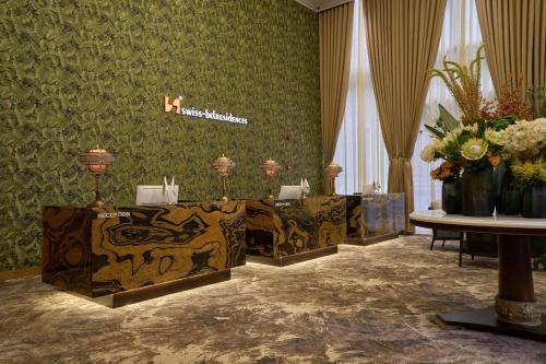 a room with green wallpaper with tables and flowers at Epic Tower Swiss-Belresidences Hanoi in Hanoi