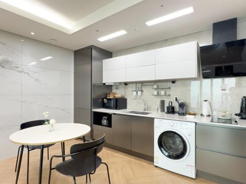 a kitchen with a washing machine and a table at Brown Suites Busan Station in Busan