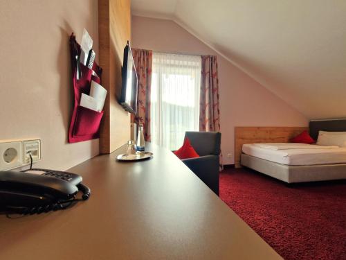 a hotel room with a desk and a bed at Mosers Blume Relax & Genuss Hotel in Haslach im Kinzigtal