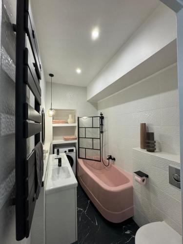La salle de bains est pourvue d'une baignoire rose et d'un lavabo. dans l'établissement Spacieux, plein centre refait à neuf, à Vienne